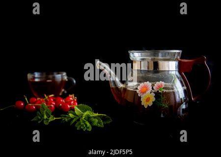 Teapot with tea and cherries on a black background Stock Photo