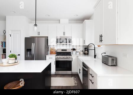 https://l450v.alamy.com/450v/2jdf607/a-modern-farmhouse-kitchen-with-a-black-island-white-marble-countertops-white-cabinets-and-stainless-steel-appliances-2jdf607.jpg