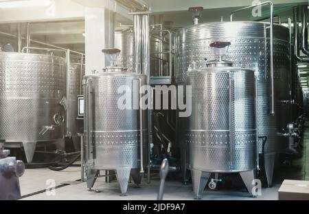 Typical steel barrels for wine fermentation in winery factory. Stock Photo