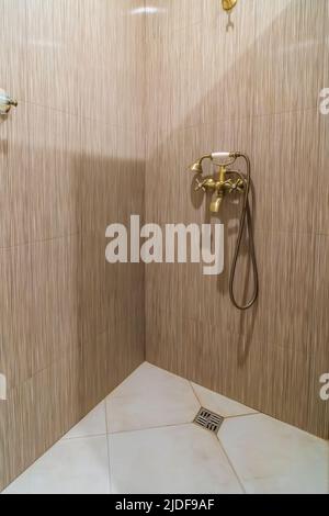 Modern shower room, shower with faucet and beige ceramic tiles, vertical photo. Stock Photo