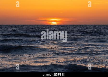Sun setting under the horizon by the North Sea, Belgium. Stock Photo