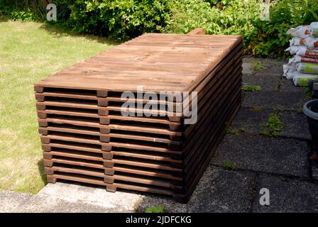 Stack of wooden fence panels, posts, gravel boards and cement mix, stored on patio ready for replacing old domestic garden fence Stock Photo