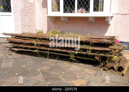 Remnants of old domestic garden fence stacked in front of house while awaiting collection for disposal Stock Photo