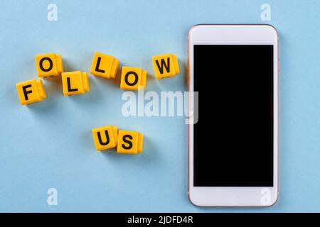 Top view smartphone and follow us words. Isolated on blue background. Stock Photo