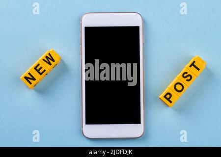 Flat lay new post concept on blue background. Close up turned-off smartphone with white frame. Stock Photo