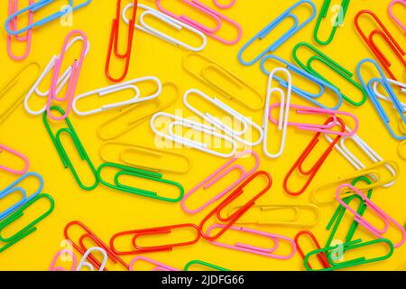 Colored paper clips on a yellow background Stock Photo