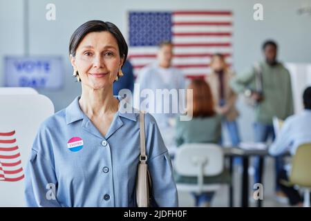 Waist up portrait of smiling mature woman with I voted sticker posing on election day, copy space Stock Photo