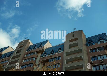 Facade of a high-rise apartment building against a blue sky with fluffy cumulus clouds. Typical city development. Multi-storey residential building in Stock Photo
