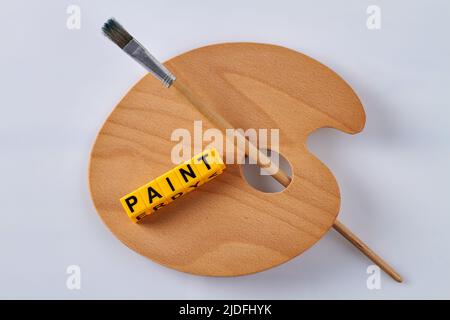 New clean wooden artist palette on white. Paint word made of wooden letter cubes. Stock Photo