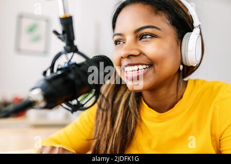 Happy african american young woman talking at online radio station from home Stock Photo