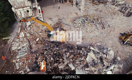 Dusty dangerous construction site. Yellow dirty digger with tracks taking down walls of a destroyed building. High quality photo Stock Photo