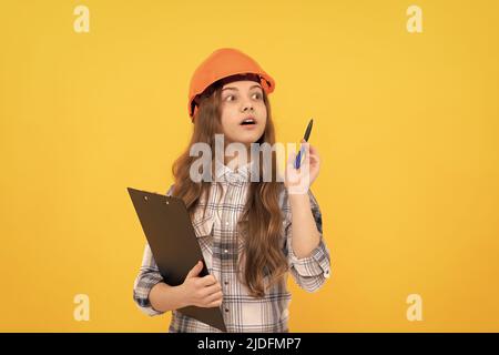 concentrated child worker wear hardhat hold clipboard. childhood development. Stock Photo