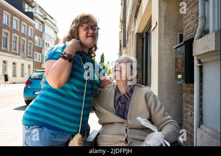 Cheerful moment between an 83 year old senior woman kissing her 39 year old daughter with the Down Syndrome, Tienen, Belgium Stock Photo
