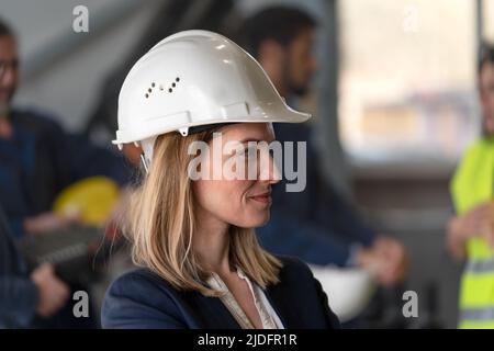 Side view of a female chief engineer in modern industrial factory looking at camera. Stock Photo