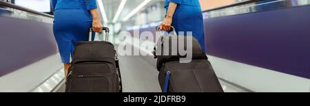 Female flight attendants carrying travel suitcases at airport Stock Photo