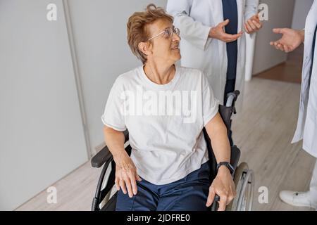 Professional doctors discuss over patient's diagnosis standing in hospital hall Stock Photo
