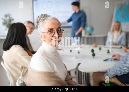 Group of senior students discussing altenrative energy with teacher in classroom. Stock Photo