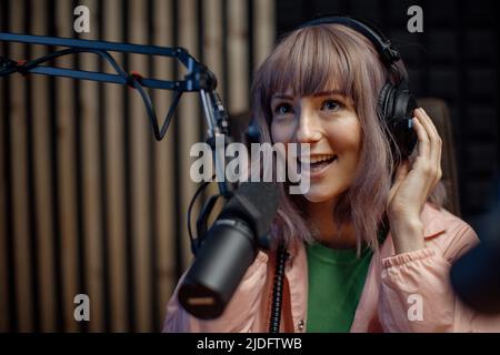 Portrait of female radio host speaking in microphone while moderating a live show Stock Photo