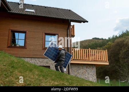 Man worker carrying solar panel for installing solar modul system on house. Stock Photo