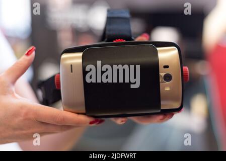 Female holds VR glasses with a smartphone. Test drive option to try out VR technology. Stock Photo