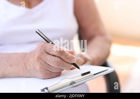 Old woman filling form in clinic or in hospice Stock Photo