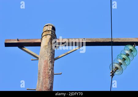 A wooden power pole against a blue sky Stock Photo