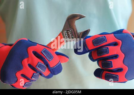 Female hands in protective work gloves holding wrench Stock Photo