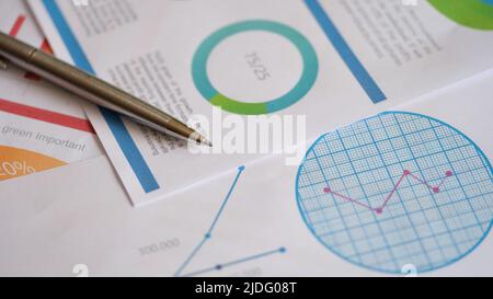 Metal pen on documents with colourful charts, graphs and diagrams Stock Photo