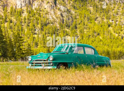 Abandoned rustic car on the hill in summer sunny day Stock Photo