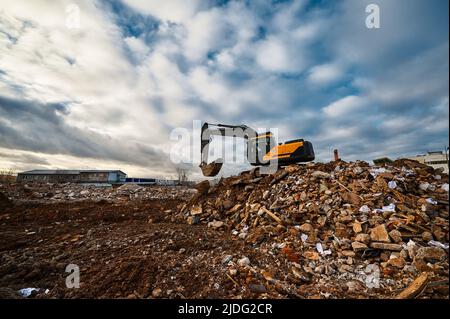 Excavator pours soil on pile of garbage at demolition site Stock Photo