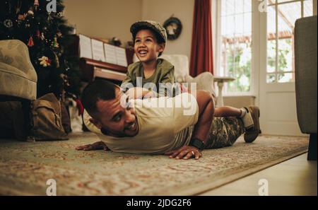 Army soldier spending quality time with his son at Christmas. Happy military dad spending the holidays with his son after deployment. Father and son h Stock Photo