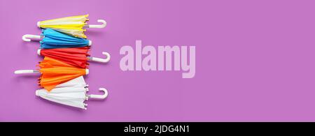 Different umbrellas on violet background with space for text Stock Photo