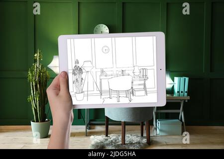 Designer holding tablet computer with drawing of new office interior with comfortable workplace Stock Photo