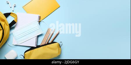 Different school supplies and medical mask on light blue background with space for text, top view Stock Photo