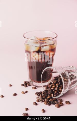 Glasses with cold brew and coffee beans on pink background Stock Photo