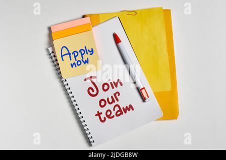 On a white background on a notepad text JOIN OUR TEAM and text APPLY NOW on yellow stiker. Consept Stock Photo