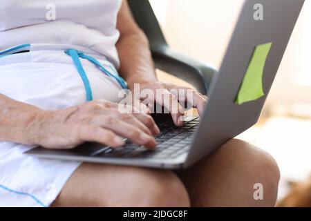 Old woman working or searching information on modern laptop Stock Photo