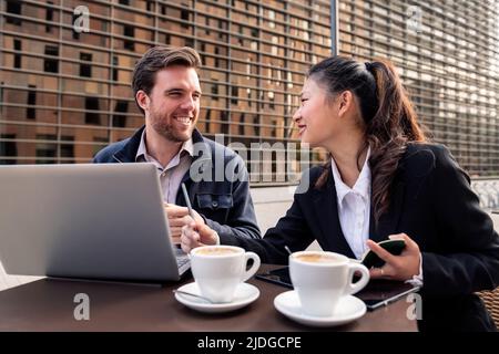 woman and man working with a laptop on a terrace Stock Photo
