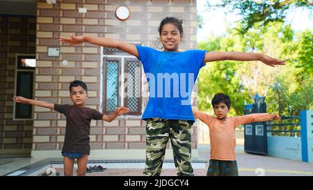 Three Indian little kids doing meditate yoga asana on roll mat with ...