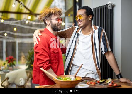 Two cool guys hugging while cooking at home Stock Photo