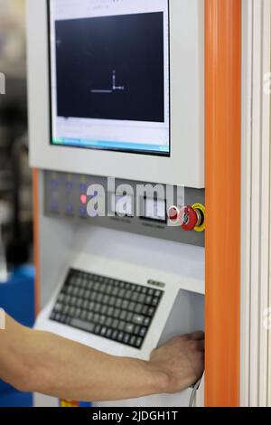 Operator controls CNC metal cutting machine. Selective focus. Stock Photo