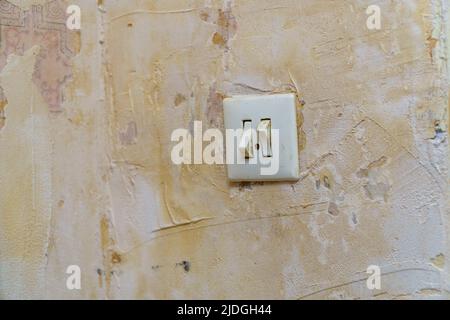 Old light switch on a shabby battered wall. Selective focus Stock Photo