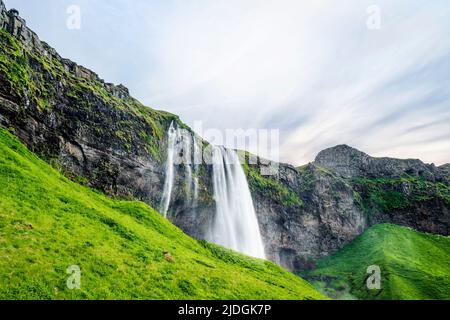 Seljalandsfoss waterfalls in Iceland with green hills and lava cliffs Stock Photo