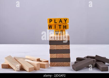 Stack of wooden blocks play with me letters. Tower building game jenga. Stock Photo