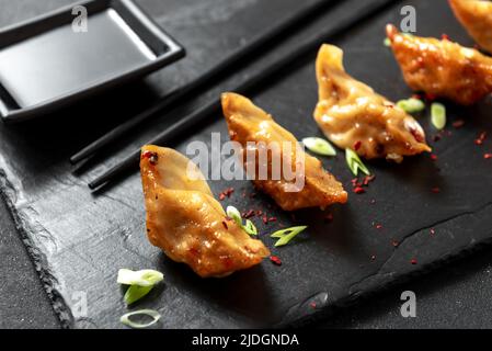 Japanese Fried Dumplings with onions on a black background. Gyoza is a very popular dish in Japan. It was originally called Chinese fried jiaoji dumpl Stock Photo
