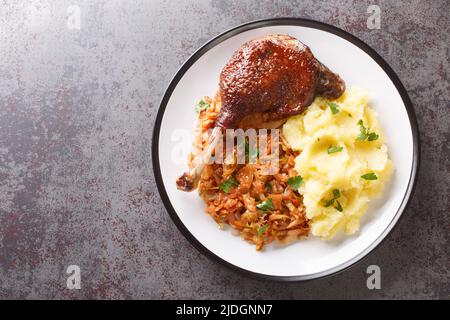 Romanian food duck leg with stewed cabbage and mashed potatoes close-up in a plate on the table. horizontal top view from above Stock Photo