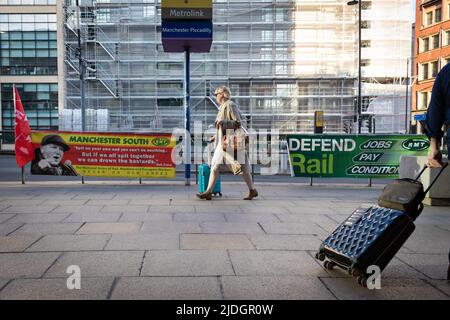Manchester, UK. 21st June, 2022. A member of the public walks past RMT banners. The biggest rail strike in over 30 years went ahead after last-minute talks failed. RMT states it has no choice but to strike due to proposed cuts to jobs, pay and pensions. Credit: Andy Barton/Alamy Live News Stock Photo