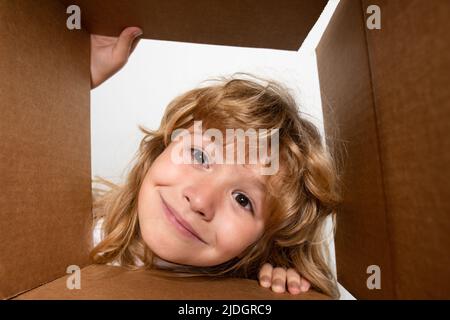 Surprised child boy unpacking, opening carton box and looking inside. The package, delivery, surprise, gift for kid. Children emotions and kids facial Stock Photo