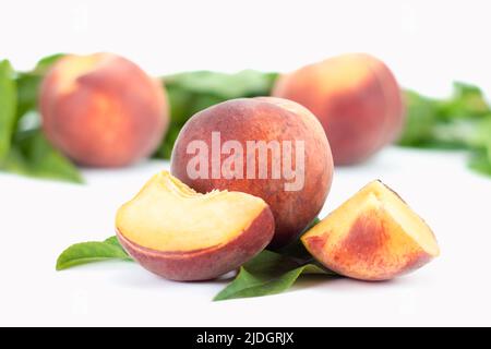 Fresh ripe peaches fruit with leaves and slice isolated on white background. Close up view. Stock Photo