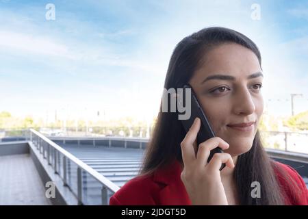 Business woman, smiling business woman talking with phone in the balcony of her office. Consulting client by phone call. Enjoying conversation. Stock Photo